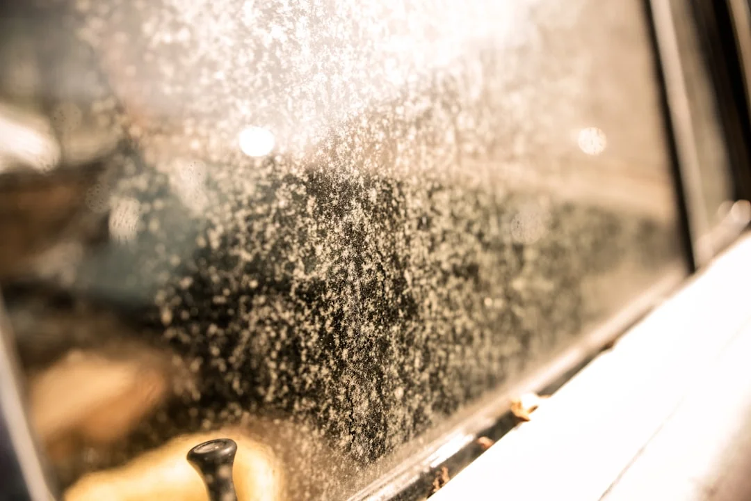 An adult male cleaning a glass window indoors, focusing on household chores and cleanliness.
